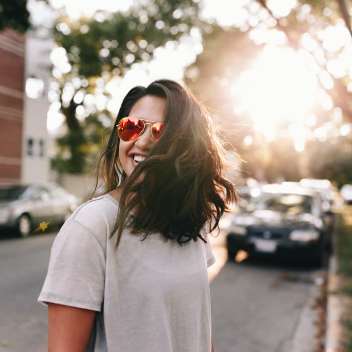Una imagen de una mujer con gafas de sol en una calle de la ciudad con retroiluminación del sol poniente