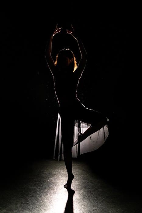 Una hermosa fotografía de ballet de una bailarina posando en el escenario con poca luz