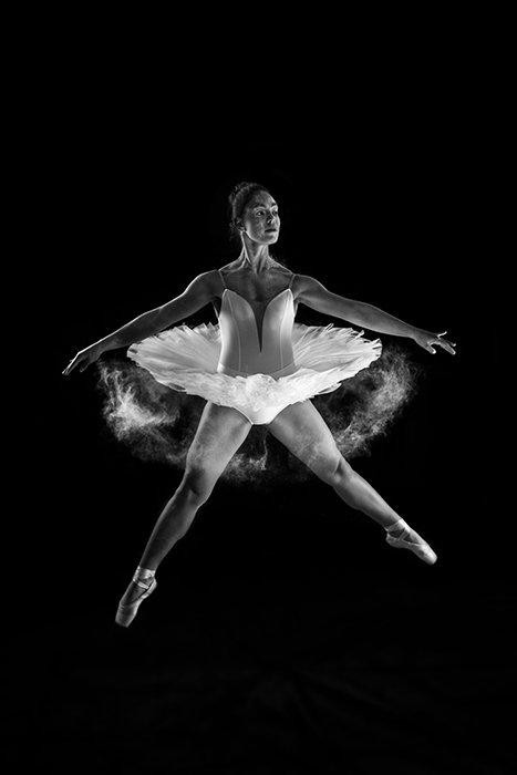 Fotografía de ballet artístico de una bailarina bailando en el escenario con poca luz