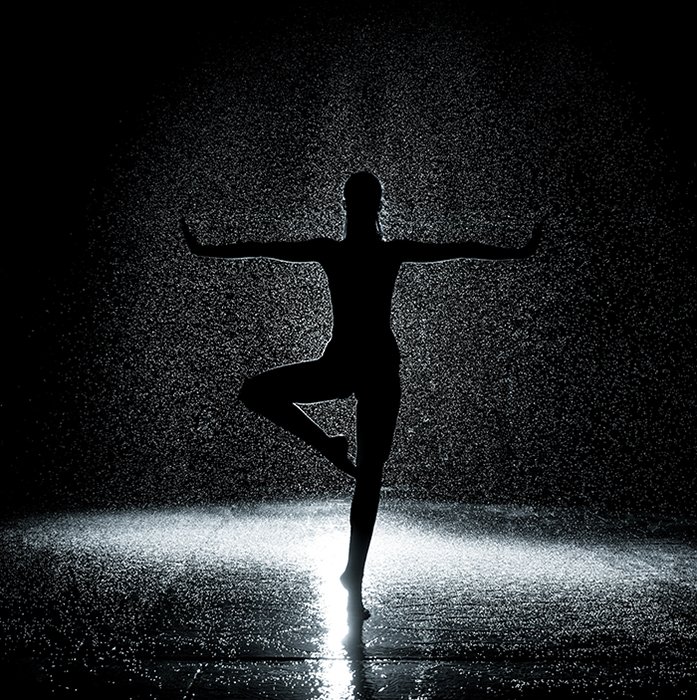 Fotografía de ballet artístico de la silueta de una bailarina bailando en el escenario con poca luz