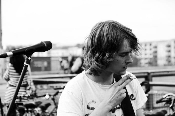 Retrato en blanco y negro de un músico fumando un cigarrillo en el escenario