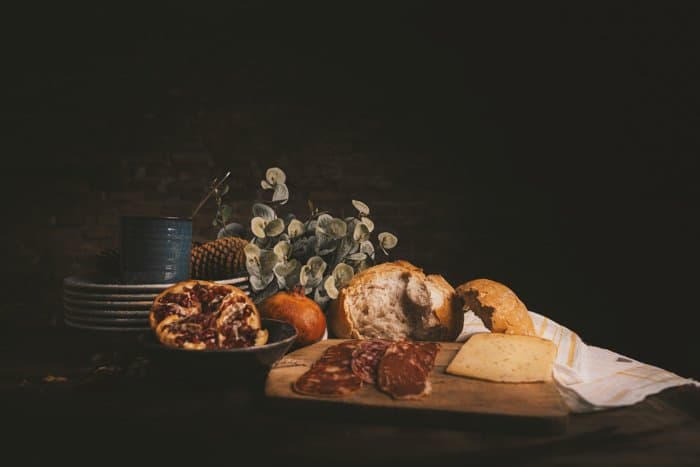 Foto de bodegón con brad, jamón, queso y platos sobre una mesa