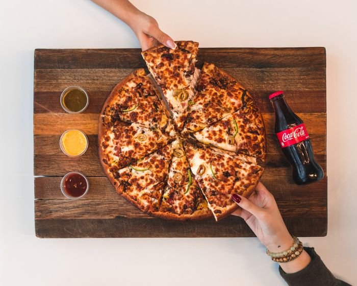 Fotografía aérea de manos tomando porciones de pizza
