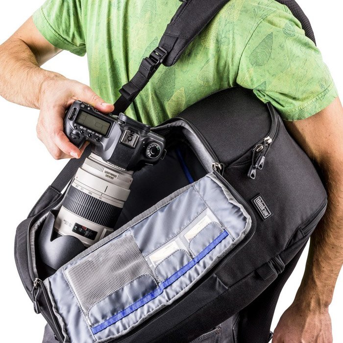   Foto de un hombre sosteniendo una mochila Think Tank Photo "Trifecta 8" Mochila sin espejo con cámara.  La mejor bolsa de cámara para fotografía callejera.
