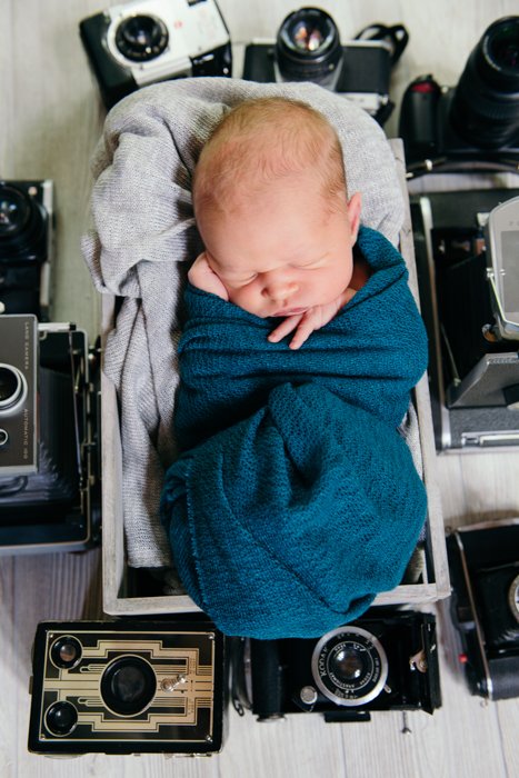 Foto de un bebé durmiendo con viejas cámaras a su alrededor.