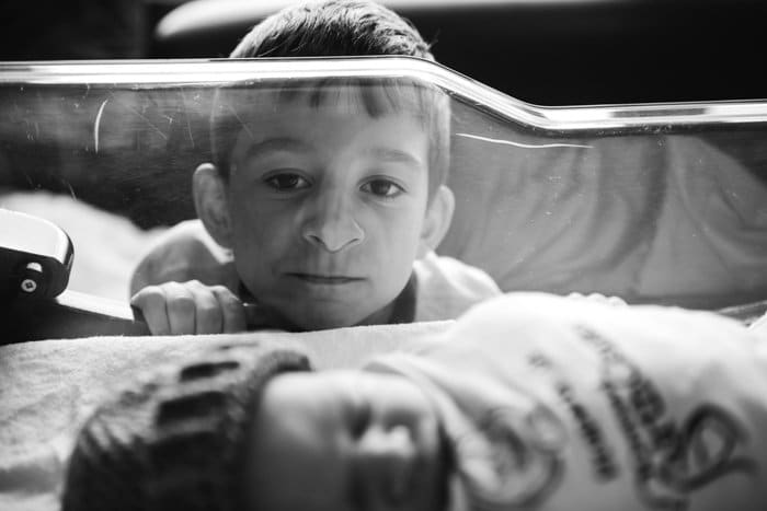 Foto de un niño mirando a su hermano durmiendo en una cuna.