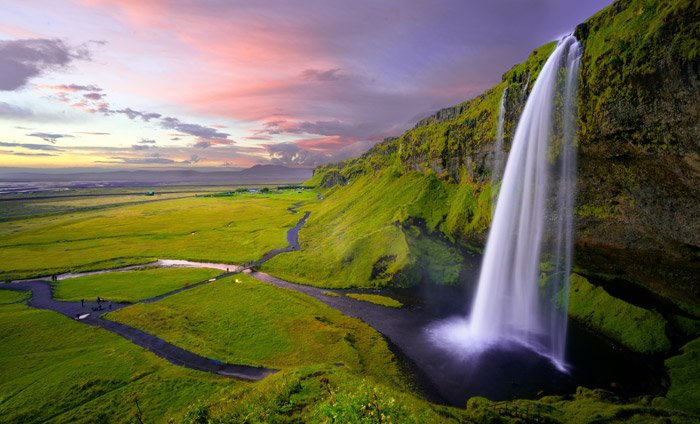 un exuberante paisaje montañoso verde con una cascada al atardecer: impresionantes fotos de paisajes