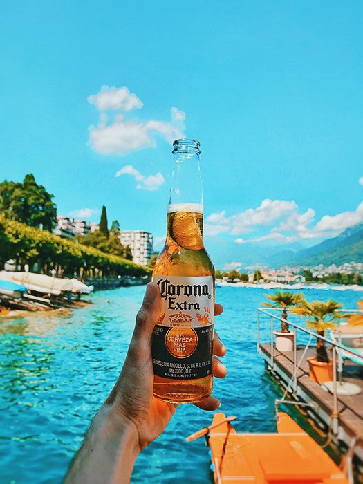 Una botella de cerveza corona contra un fondo tropical - fotos de cerveza