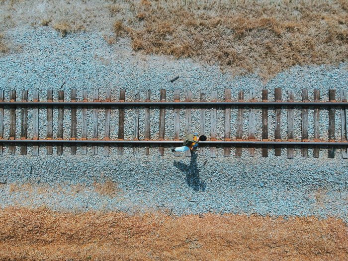 Un ángulo de la cámara de vista de pájaro de un hombre caminando por las vías del tren