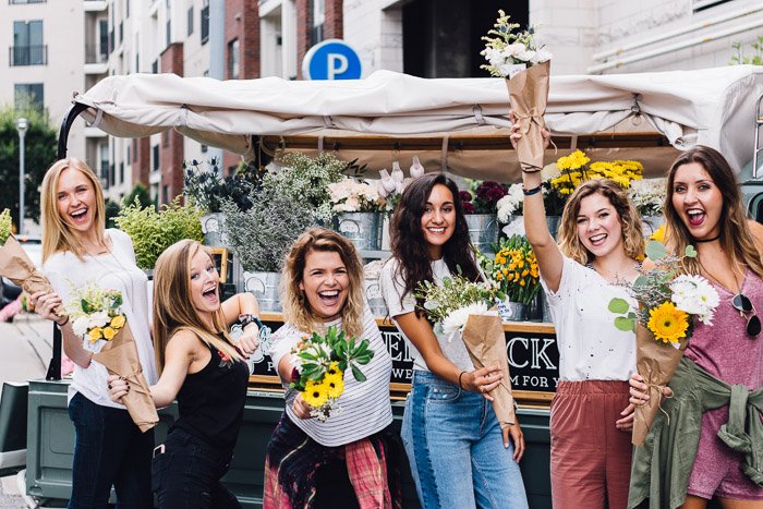 Divertida foto de grupo de chicas sosteniendo ramos de flores y sonriendo