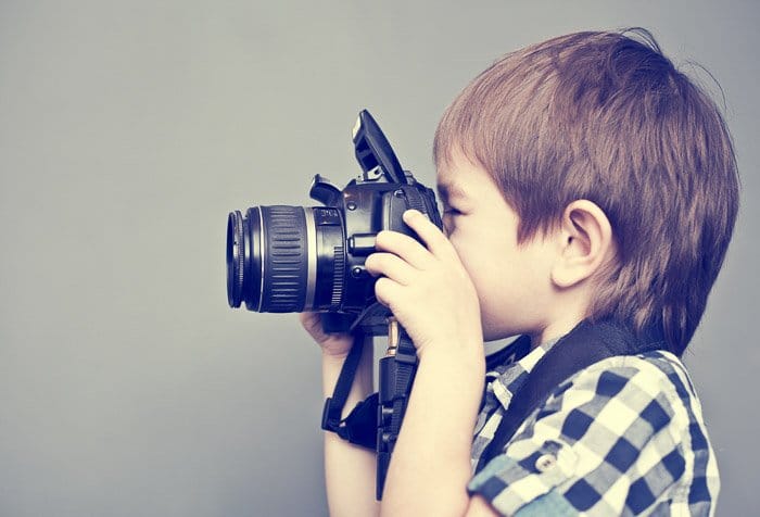 Dulce retrato de un joven sosteniendo una cámara DSLR 