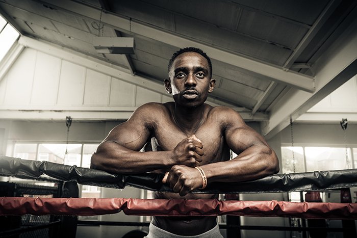 Fotografía de boxeo atmosférico de un luchador apoyado contra las cuerdas en un gimnasio