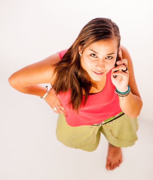 Un ejemplo de composición de fotografía de una mujer morena con una camisa roja hablando por su teléfono celular mirando hacia arriba