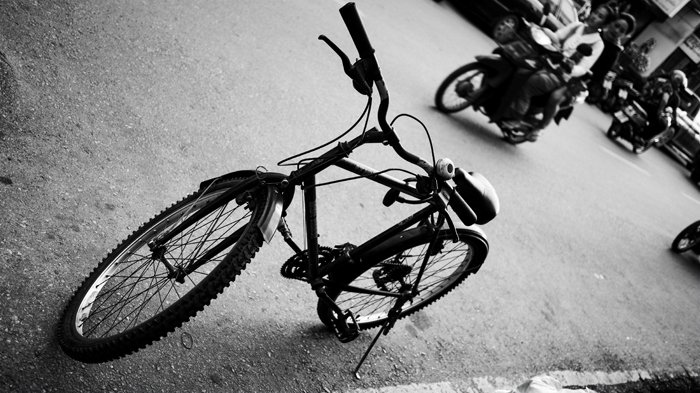 Una fotografía en blanco y negro en ángulo de una bicicleta estacionada en la calle.