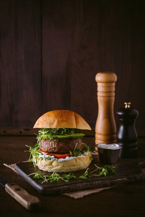 Una deliciosa configuración de fotos de hamburguesas en tablero rústico y fondo