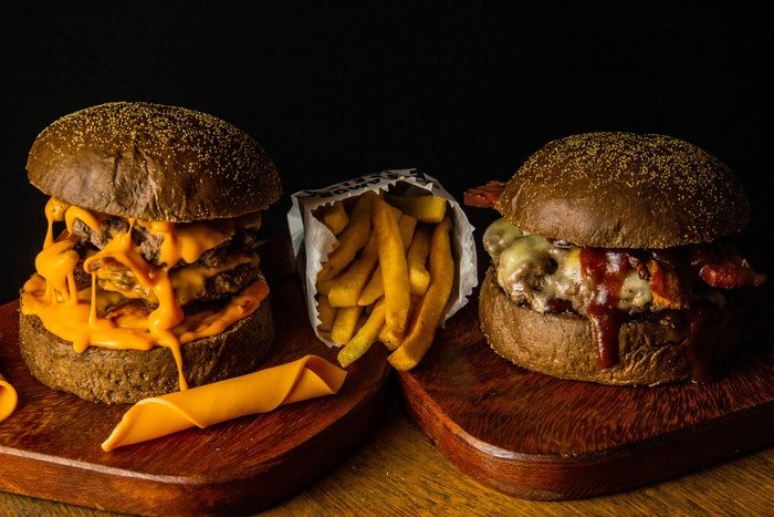 Foto a la altura de los ojos de dos hamburguesas con papas fritas en el medio