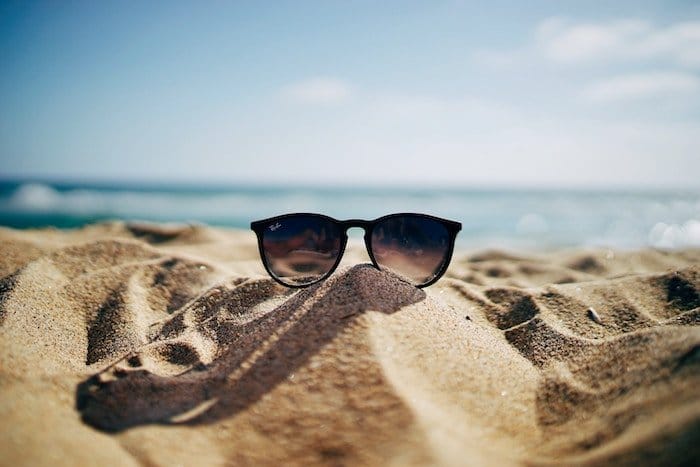 Foto de gafas de sol rodada en la playa en la arena