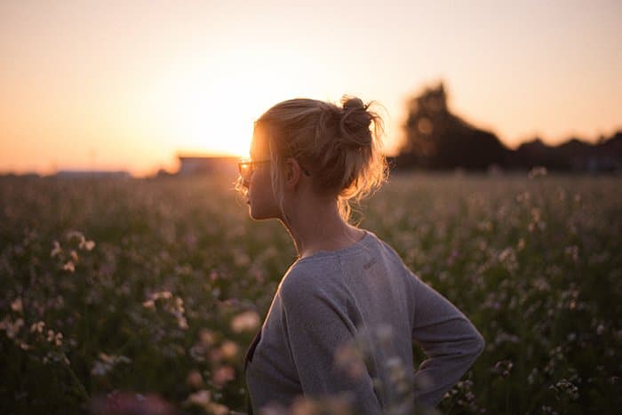 Un sincero retrato de una modelo femenina en un prado al atardecer