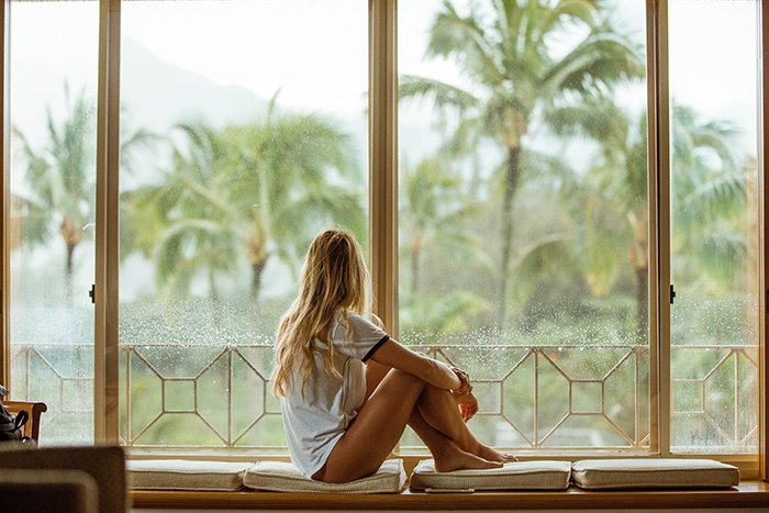 Una foto de estilo de vida sincero de una modelo femenina mirando por una ventana 