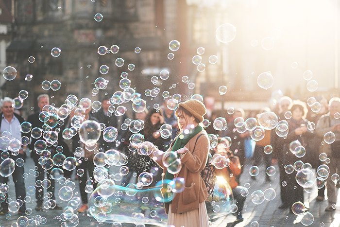 Una fotografía callejera de una mujer jugando con burbujas al aire libre 