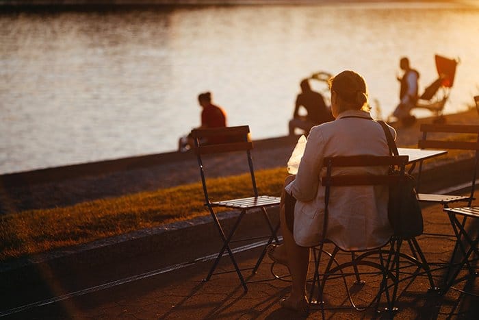 Gente sentada junto a un río al atardecer 