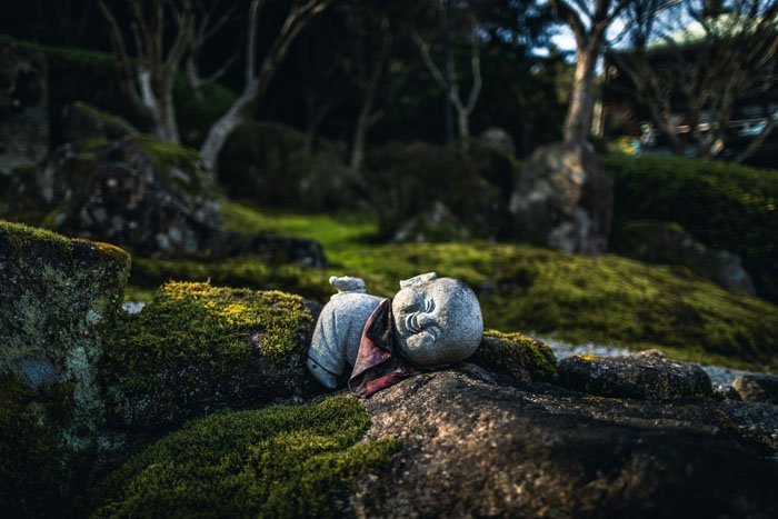 Una pequeña estatua de piedra de Buda en un bosque.