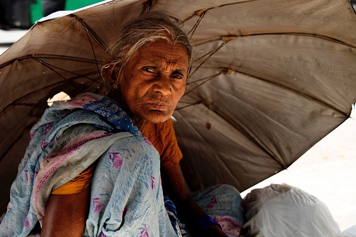 Una anciana escondida bajo una sombrilla del sol: la mejor luz del día para retratos 