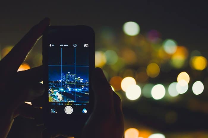 Una persona que toma fotografías de la calle por la noche con un teléfono inteligente.