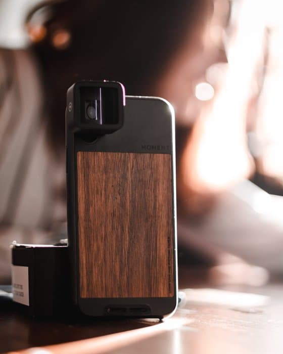 una imagen de un teleobjetivo para iphone con una funda de madera