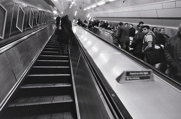 Personas que viajan por las escaleras mecánicas en Londres - fotografía callejera en blanco y negro