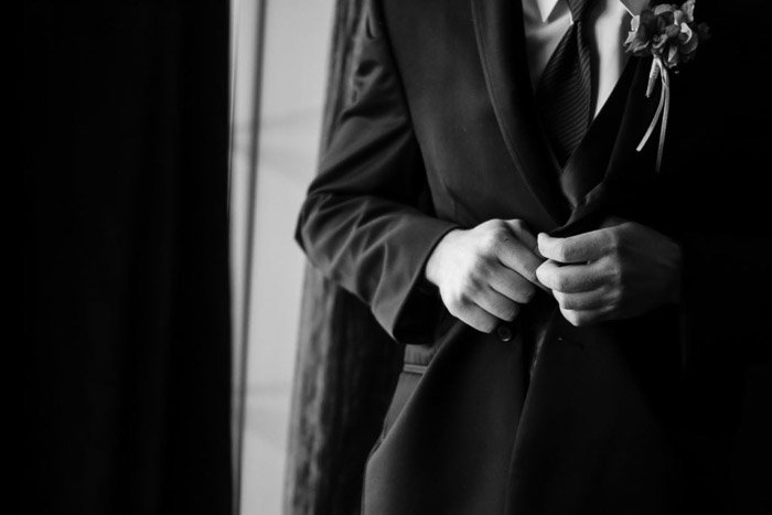 Una foto de boda en blanco y negro de un novio abrochando su chaqueta