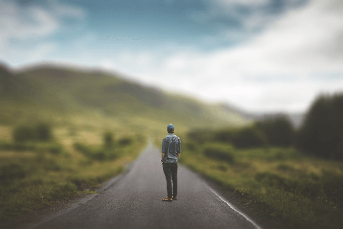 Un hombre parado en medio de la carretera, fondo de paisaje borroso