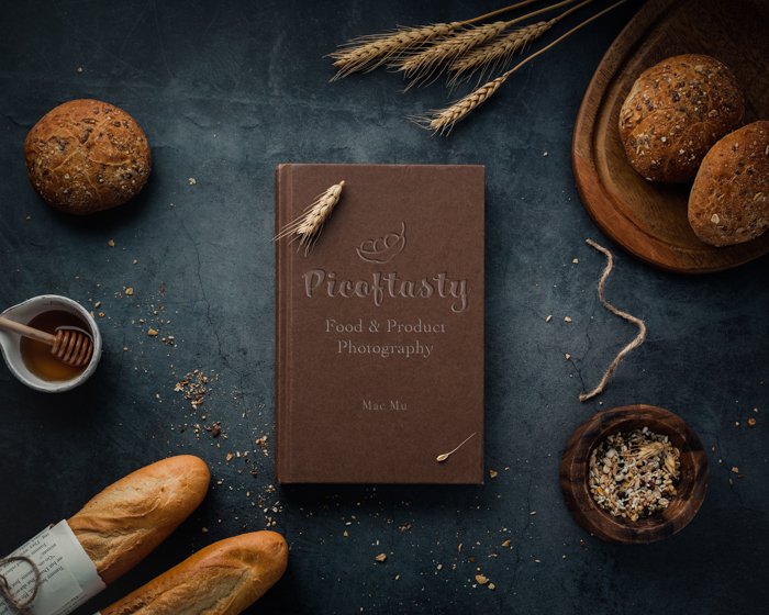 Fotografía de producto imagen aérea de un libro de cocina sobre una mesa con pan y trigo