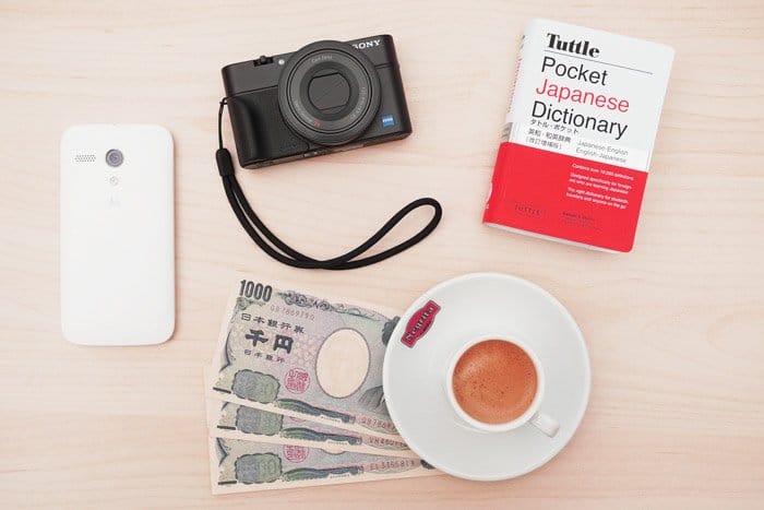 Accesorios para fotografía de viajes como guía, cámara, dinero local y teléfono