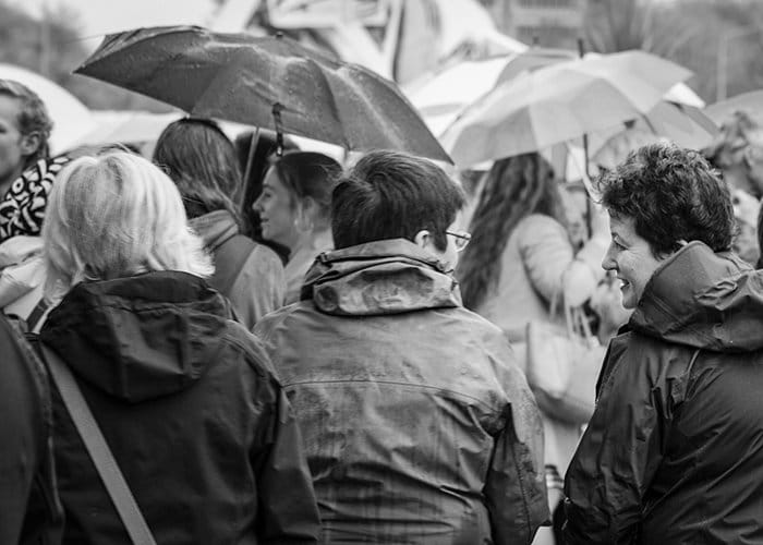 Fotografía callejera en blanco y negro de un grupo de adultos bajo la lluvia.  Fotografía de lluvia
