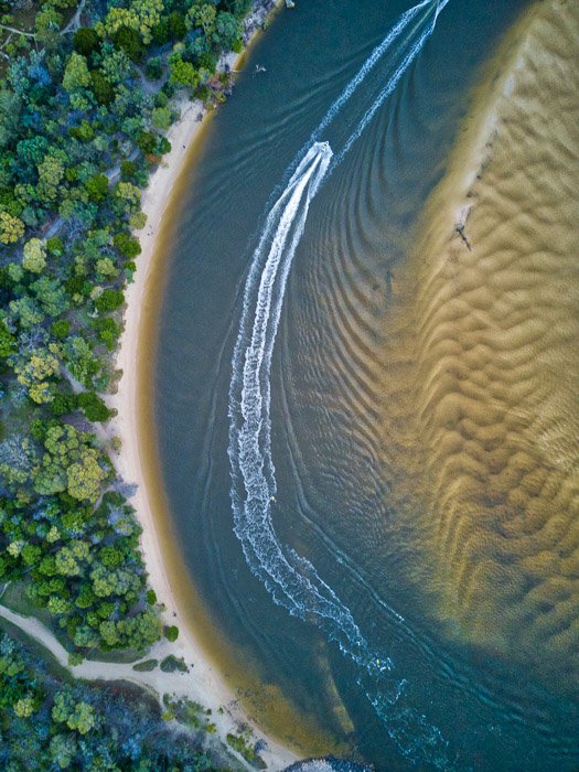Fotografía con drones que captura las texturas contrastantes de un bosque, costa, agua y arena.