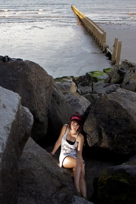 Un retrato de una modelo femenina posando sobre las rocas en la playa - retratos interesantes