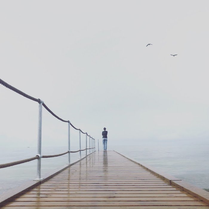Fotografía minimalista: una imagen minimalista de una persona parada al final de un muelle.