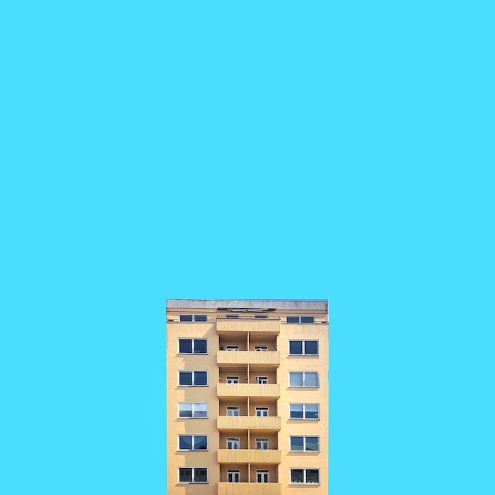 Fotografía de arquitectura minimalista de un edificio simétrico contra un fondo azul.