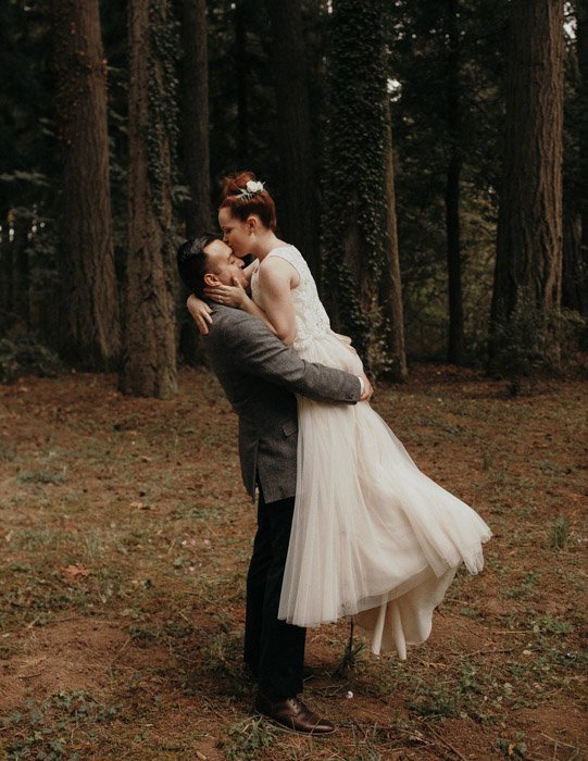 Fotografía de la boda de Jordan Voth de una pareja de recién casados ​​besándose en el bosque.  Fotógrafos de retratos famosos 