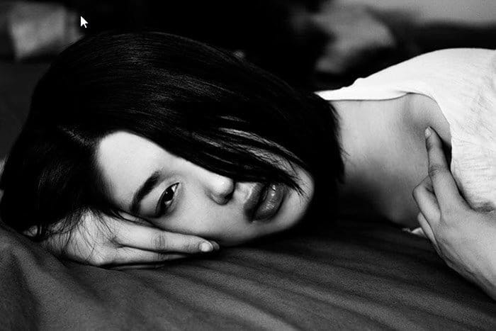 Andi Elloway retrato en blanco y negro de una niña en una cama.  Fotógrafos de retratos famosos 