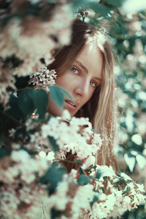 Federico Sciuca retrato cinematográfico de una niña mirando a través de flores.  Fotógrafos de retratos famosos 