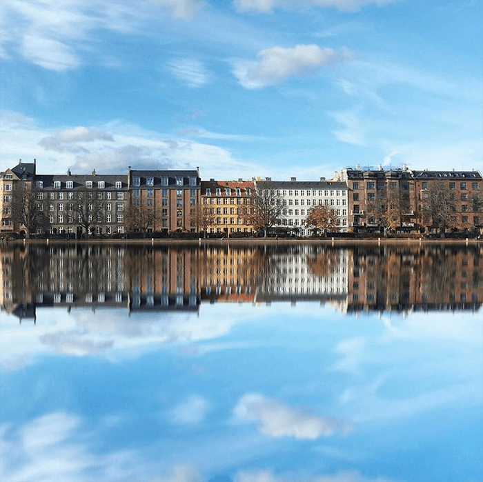 Fotografía de paisaje urbano: reflejos de edificios, nubes y cielo azul en Copenhague, Dinamarca