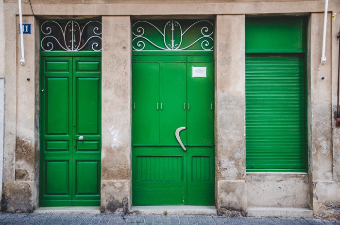 Foto de la fachada de un edificio con puertas y contraventanas de color verde esmeralda: el tema de este paseo fotográfico fueron los rectángulos.
