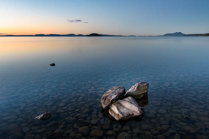 Un grupo de rocas en un mar en calma al atardecer.  Composición de fotografía de paisaje