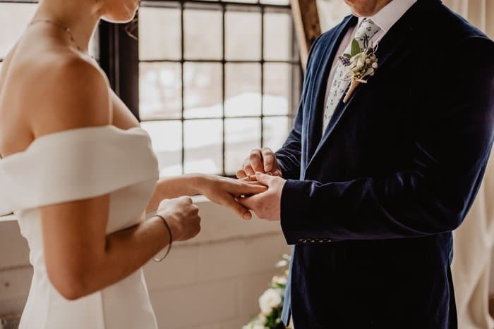 Cerca de la novia y el novio tomados de la mano durante una ceremonia de boda