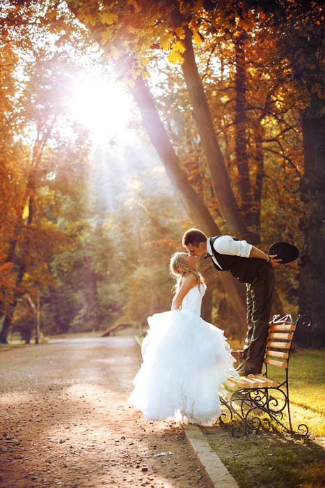 Imagen atípica del novio de pie en un banco mientras le da un beso a la novia