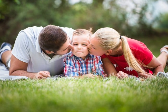 retrato de familia posa madre padre e hijo acostados en la hierba