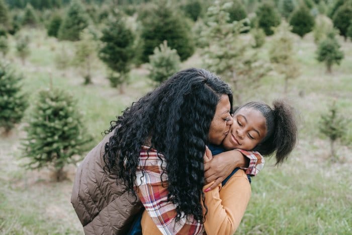 madre besando a su hija en una zona verde