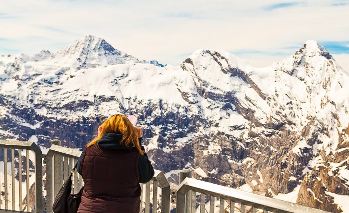 foto de una niña mirando desde un mirador a las montañas rocosas cubiertas de nieve